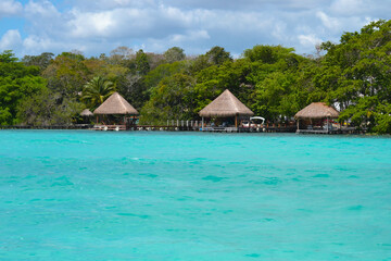 Vintage rustic wooden jetties photographed from a ship with famous seven shades of bluish water overwater bungalows on the end of the pier, Caribbean idyllic peaceful coast on a cloudy and sunny day