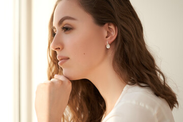 Fashionable portrait of a young beautiful girl with jewelry. Earrings with white crystals and diamonds.