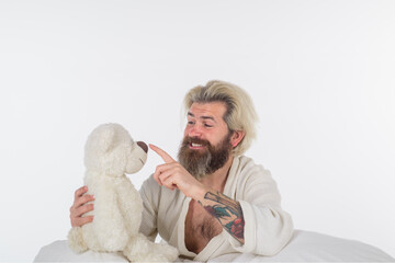 Man play with teddy bear in bed. Man sleep in bed. Bearded man in bed with toys. Morning and wake up. Nap. Man sleeping with teddy bear. Teddy bear. Sleeping toy.