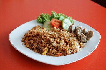 Indonesian fried rice with beef meatballs. fresh tomato lettuce and cucumber