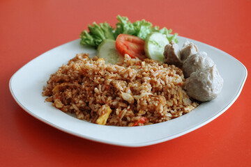 Indonesian fried rice with beef meatballs. fresh tomato lettuce and cucumber