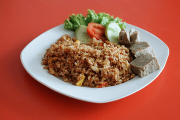 Indonesian fried rice with beef meatballs. fresh tomato lettuce and cucumber