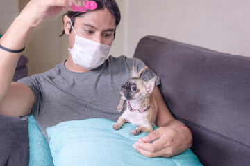 persona joven con cubrebocas en casa con su mascota 