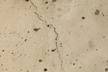 Detailed close up of buff coloured concrete wall with surface patterns, textures and a crack. Grunge background with copy space.