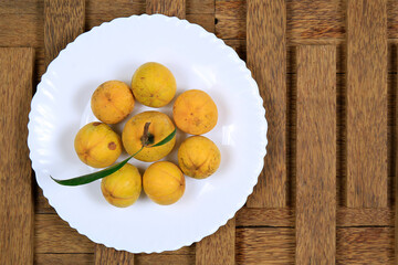 Naklejka na ściany i meble Fresh ripe tasty eggfruits in a white bowl isolated on wooden background