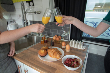 A celebration breakfast is served in this trendy renovated camper van, includes eggs, croissants, orange juice etc served on wooden kitchen surface and grey tiled kitchen area