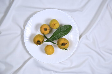 Fresh tasty eggfruit with leaves on a white bowl