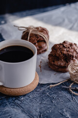 White cup of coffee and chocolate cookie on black stone background. Sweet, copy. Homemade cookies with chocolate.