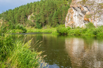 Fototapeta na wymiar Picturesque landscape with forest, cliff and reflection in the river