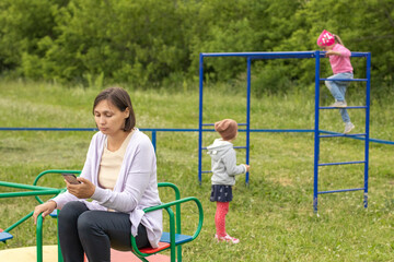 Mom looks at her phone and does not monitor children at the playground