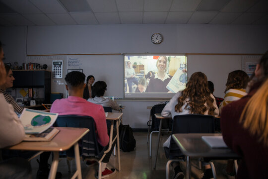 High school students watching video on projection screen in classroom