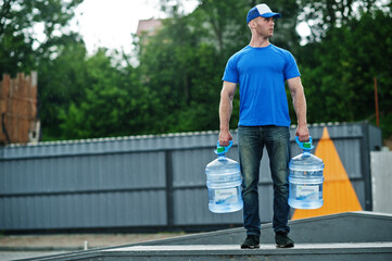 Delivery man with water bottles at hands.