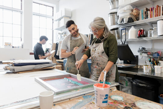 Mature Woman Screenprinting In Studio With Man