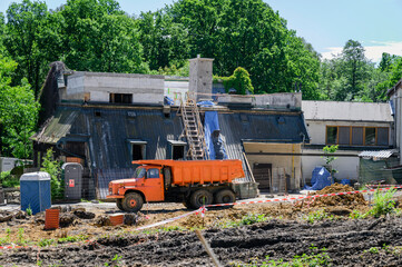 Orange Tatra truck on a construction site near a tarpaulin building.