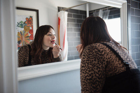 Mature Woman Doing Makeup In Bathroom Mirror