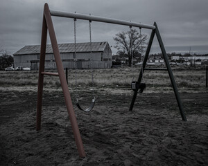Fototapeta premium Brightly colored metal swing tied with chains on a cloudy day