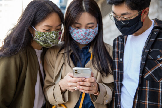 Brother and sisters in face masks using smart phone