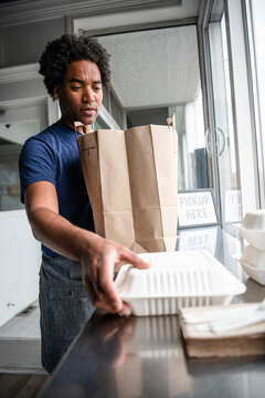 Male Business Owner Bagging Takeout Food In Cafe