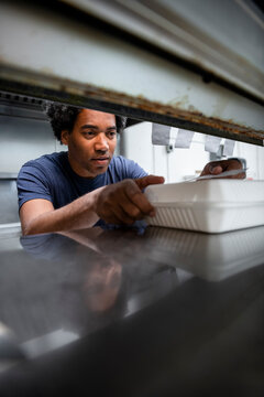 Male Chef Preparing Takeout Food In Cafe Kitchen