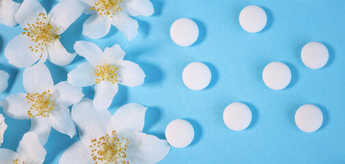 Pharmaceutical medical white pills, white flower natural medicine concept. on a blue background. Soothing medicines. View from above.