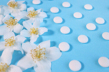 Pharmaceutical medical white pills, white flower natural medicine concept. on a blue background. Soothing medicines. View from above.