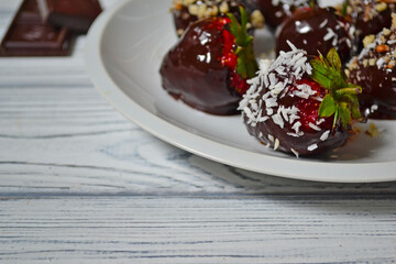 Fresh strawberries dipped in dark chocolate on white plate