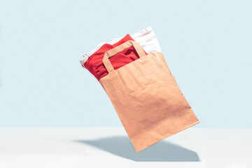 Flying shopping paper bag with purchases. Concept of consumerism, ease of shopping. Copy space trend pastel colors.