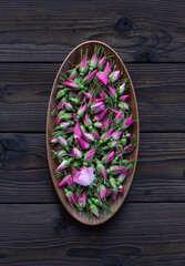 Rosehip buds in an oval wooden bowl on a dark wooden background. Fresh rosehip buds harvest for tea or making essences. For cooking, medical and cosmetology