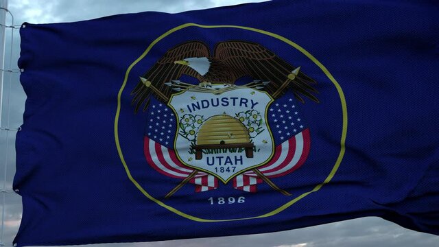 Flag of Utah waving in the wind against deep beautiful clouds sky