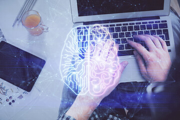 Double exposure of man's hands typing over computer keyboard and brain hologram drawing. Top view....
