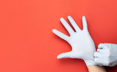 Medical antibacterial lab glove holding - Virus protection equipment on red background. COVID middle East respiratory syndrome coronavirus. Professional safety and hygiene for surgery.