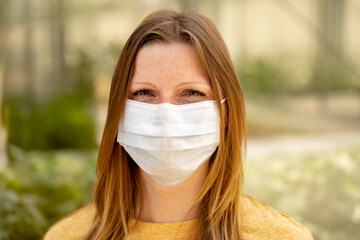 Portrait of caucasian female wearing white protective face mask. woman looking to camera. Covid-19,...