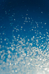 Blurred water drops on sky background, bokeh on blue background.