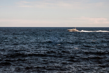 Speed Motor Boat Gliding Sea Waves under Blue Sky near Cap Ferrat Cape in Nice City, France - Entering Frame Position