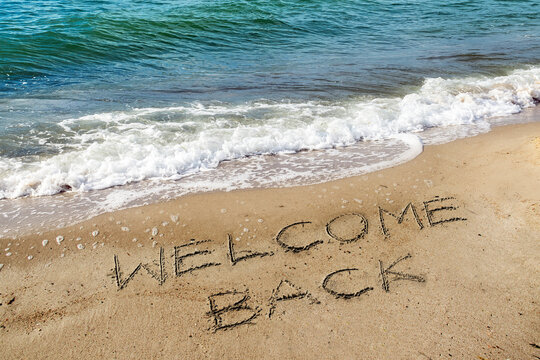 Words Welcome Back are written in the sand on the beach for the tourists, reopen after the coronavirus pandemic, sea holidays are possible again - Powered by Adobe