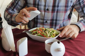 Photo for the restaurant menu. A young guy in a checkered shirt eats chicken salad with mayonnaise.