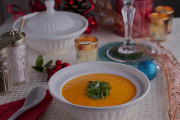 Christmas starter vegetable soup with festive decorations in the background.