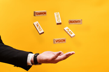 Strategy concept. man throws up wooden blocks with the inscriptions Plan, Vision, Tactics, creativity, Teamwork