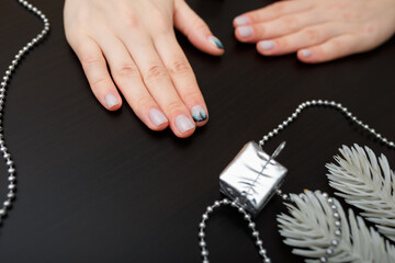 Female hands with fir-tree forest manicure and some artificial branches on black background. Christmas or winter nail art. Hands care, fingernails design, beauty and health concept. Copy space.