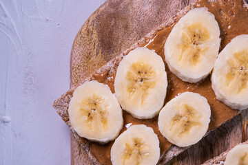 Crispbread with banana and peanut butter on a wooden table. Healthy snack. Close up view.