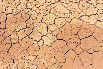Dried cracked earth soil ground texture background. Mosaic pattern of sunny dried earth soil.