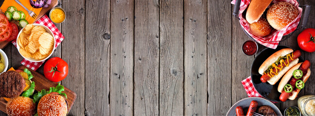 Summer BBQ food double side border with hot dog and hamburger buffet. Top view over a dark wood background. Copy space.