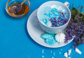 Blue moon milk decorated with mint flowers and meringue crumbs on a bright blue background