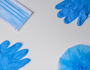 
medical gloves, mask and hat on a white background with a place for text in the middle, top view close-up.