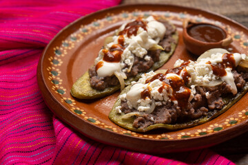 Mexican nopal cactus huaraches with cheese and beans on wooden background