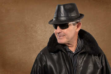 Older man wearing leather hat, jacket and sunglasses