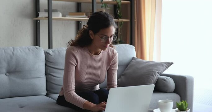 Serious young woman in eyewear working remotely on computer, feeling stressed about information or electronic report loss. Depressed unhappy female distant worker received email with dismissal notice.