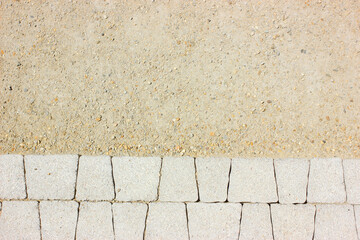 Gray paving slabs in the process of laying on sand.