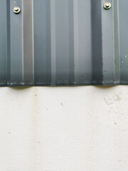 close up yellowish conrete wall and dark grey zinc