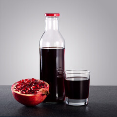 Glass and bottle of pomegranate juice and pomegranate fruit.